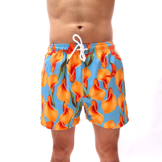 Person wearing orange floral swim shorts on a white background