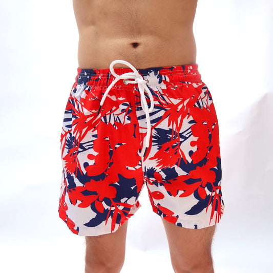 Red, white, and blue floral patterned swim shorts on a white background